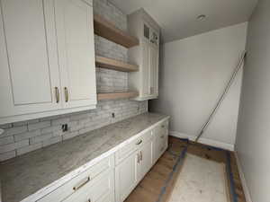 Kitchen with open shelves, glass insert cabinets, tasteful backsplash, and white cabinetry