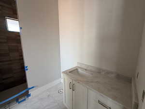 Bathroom with vanity, a walk in shower, and light marble finish floors