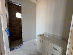 Bathroom featuring vanity, walk in shower, and light marble finish floors