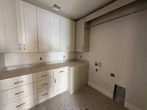 Laundry room with hookup for a gas dryer, hookup for a washing machine, cabinet space, dark aggregate flooring, and electric dryer hookup