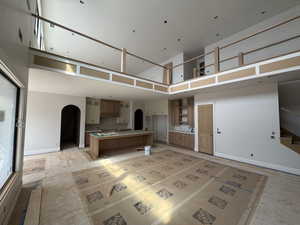 Kitchen with a spacious island, a high ceiling, backsplash, arched walkways, and open floor plan