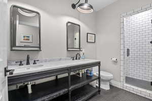 Bathroom featuring a stall shower, double vanity, and tile patterned floors
