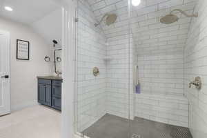 Bathroom featuring a stall shower, vanity, and lofted ceiling