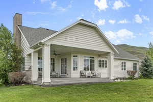 Back of house with ceiling fan, roof with shingles, a yard, a patio area, and a chimney
