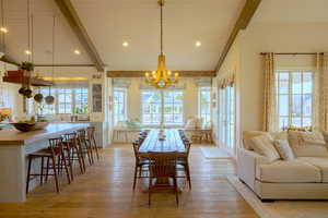 Dining space featuring lofted ceiling with beams, suspended lighting, light wood-style floors, plenty of natural light, and wood ceiling