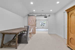 Office with a barn door, recessed lighting, light carpet, and vaulted ceiling