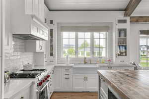 Kitchen with butcher block counters, glass fronted cabinets, white cabinets, premium stove, and light wood-type flooring