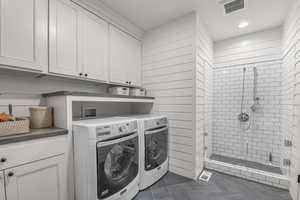 Laundry room with dark tile patterned flooring, separate washer and dryer, recessed lighting, wooden walls, and cabinet space