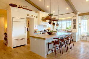 Kitchen with glass insert cabinets, a kitchen breakfast bar, a center island, paneled refrigerator, and light wood-type flooring