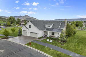 View of front of property featuring covered porch, a standing seam roof, a mountain view, driveway, and a front lawn