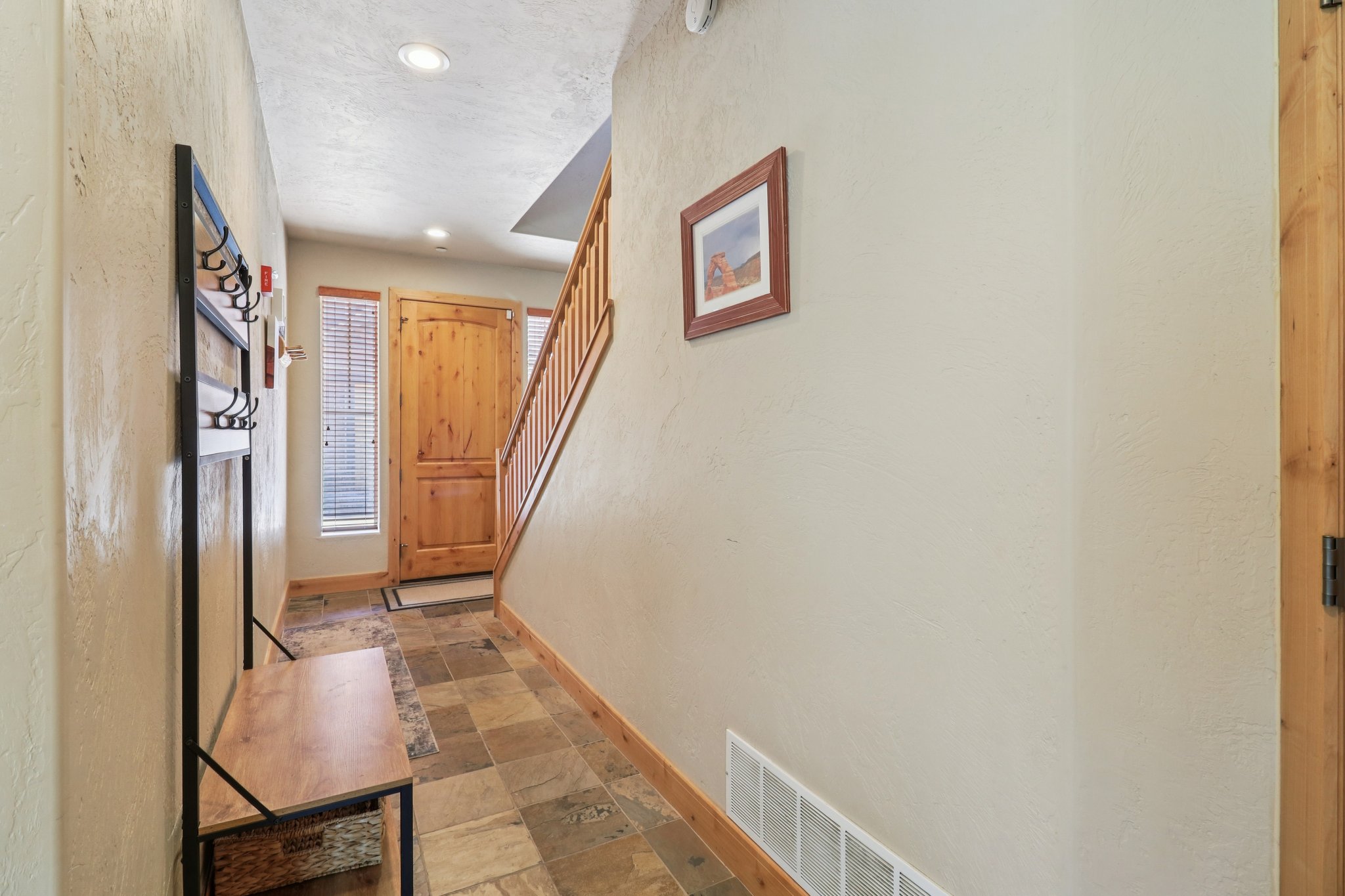 Doorway to outside featuring stone tile floors, a textured wall, and recessed lighting