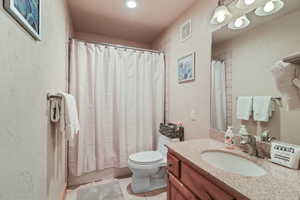 Bathroom with a textured wall, vanity, light tile patterned floors, and shower / bath combination with curtain