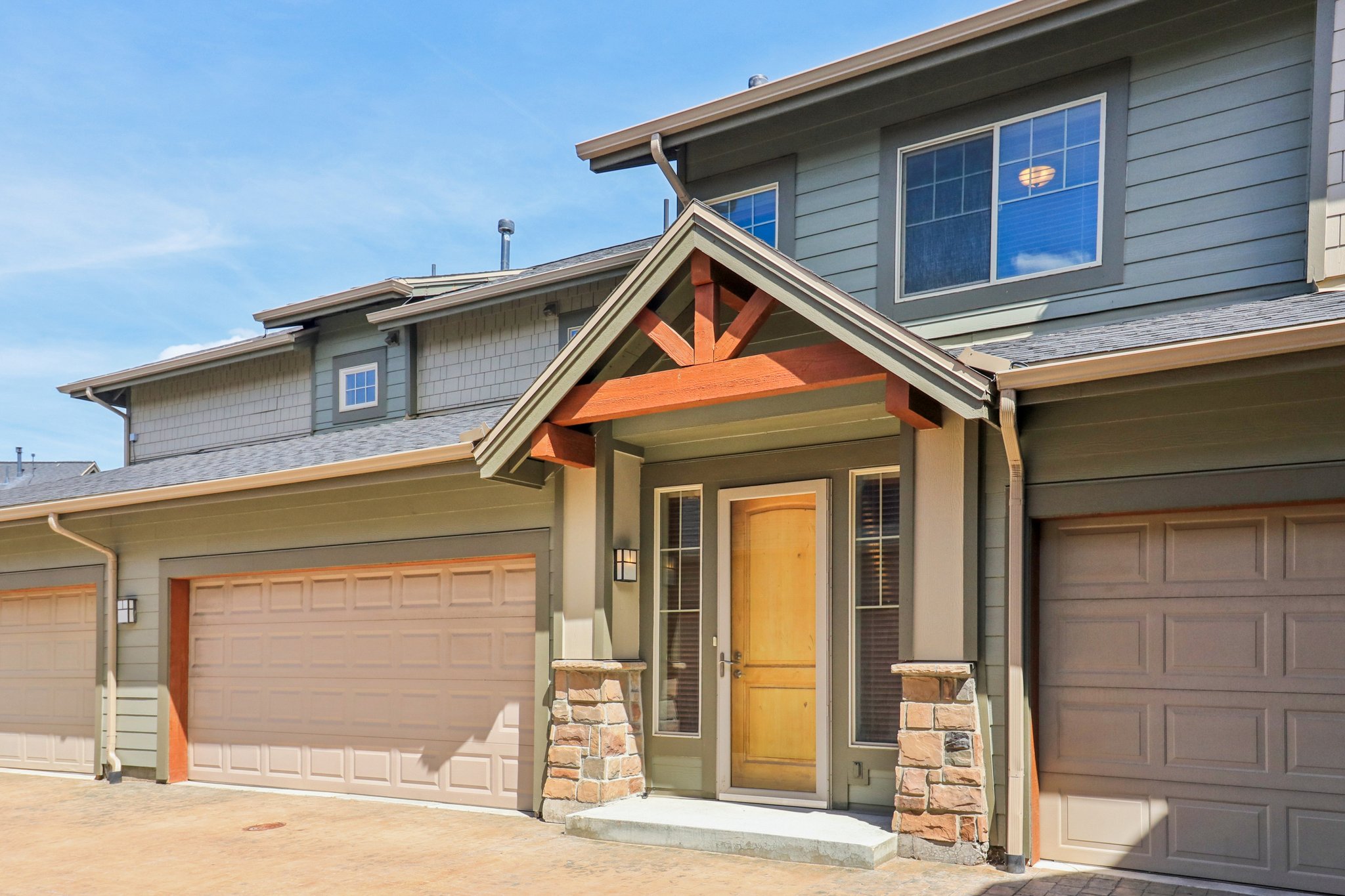 Craftsman inspired home with a garage, driveway, and stone siding