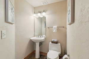 Half bathroom with tile patterned flooring and a textured wall