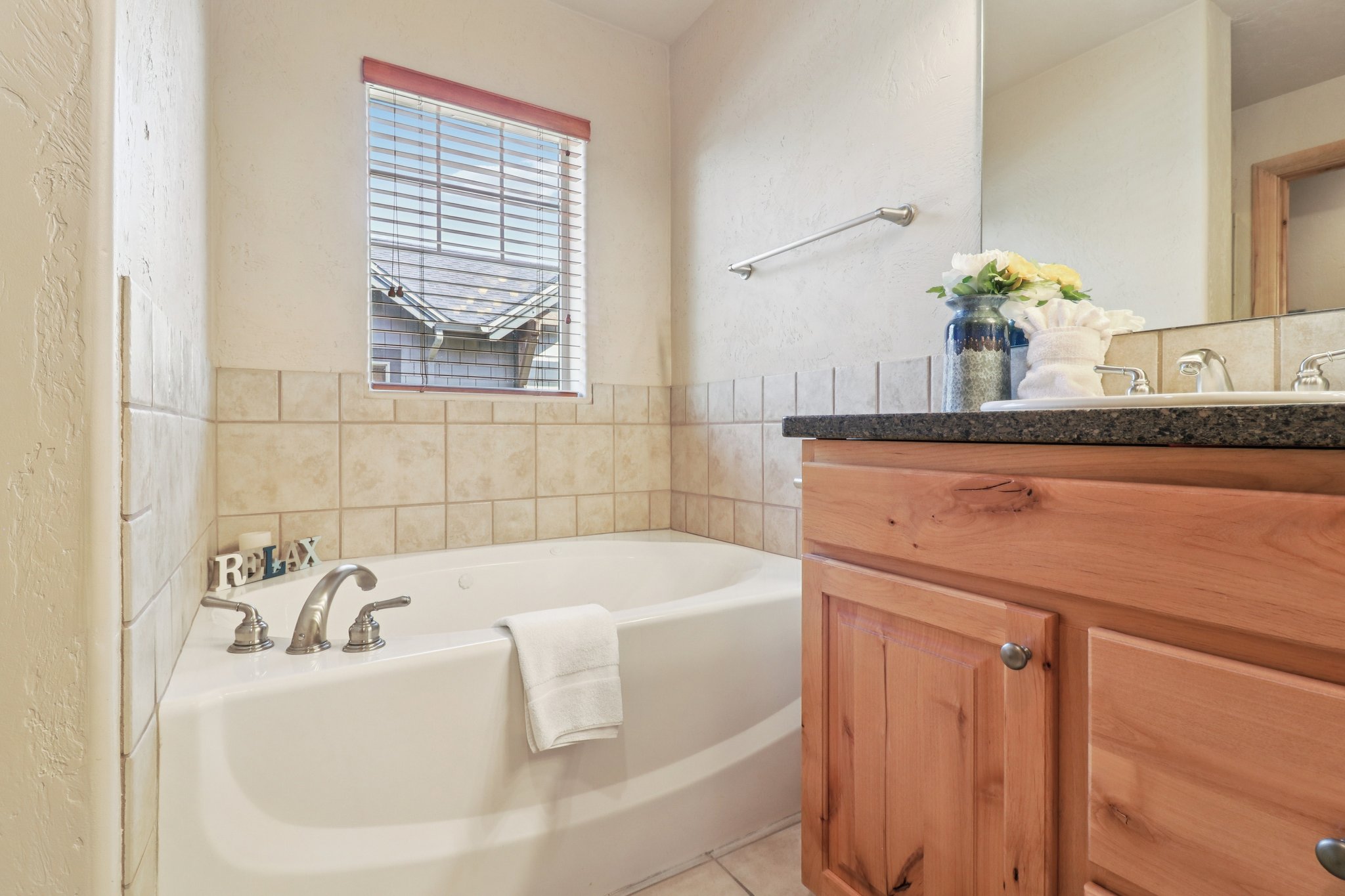 Bathroom featuring vanity, a garden tub, and a textured wall