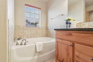 Bathroom featuring vanity, a garden tub, and a textured wall