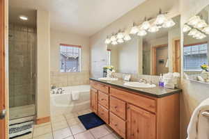 Bathroom featuring double vanity, a bath, a stall shower, and light tile patterned floors