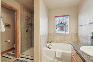Full bathroom featuring vanity, a stall shower, a garden tub, and light tile patterned flooring