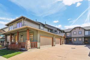 Craftsman house featuring decorative driveway, covered porch, and an attached garage