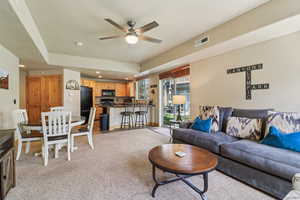Living room featuring ceiling fan, recessed lighting, light carpet, and a raised ceiling