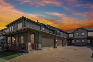 View of front of home featuring driveway, covered porch, and a garage