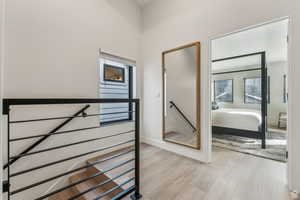 Hall with an upstairs landing and light wood-style floors