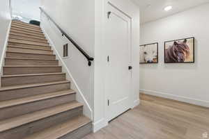 Stairs featuring wood finished floors and recessed lighting