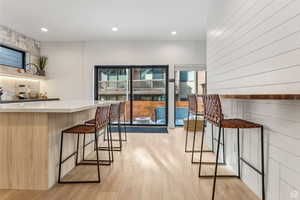 Bar area featuring light wood-type flooring, light countertops, recessed lighting, and wooden walls