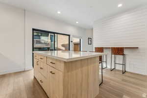 Kitchen with light wood finish cabinets, a kitchen island, light wood finished floors, a breakfast bar, and recessed lighting