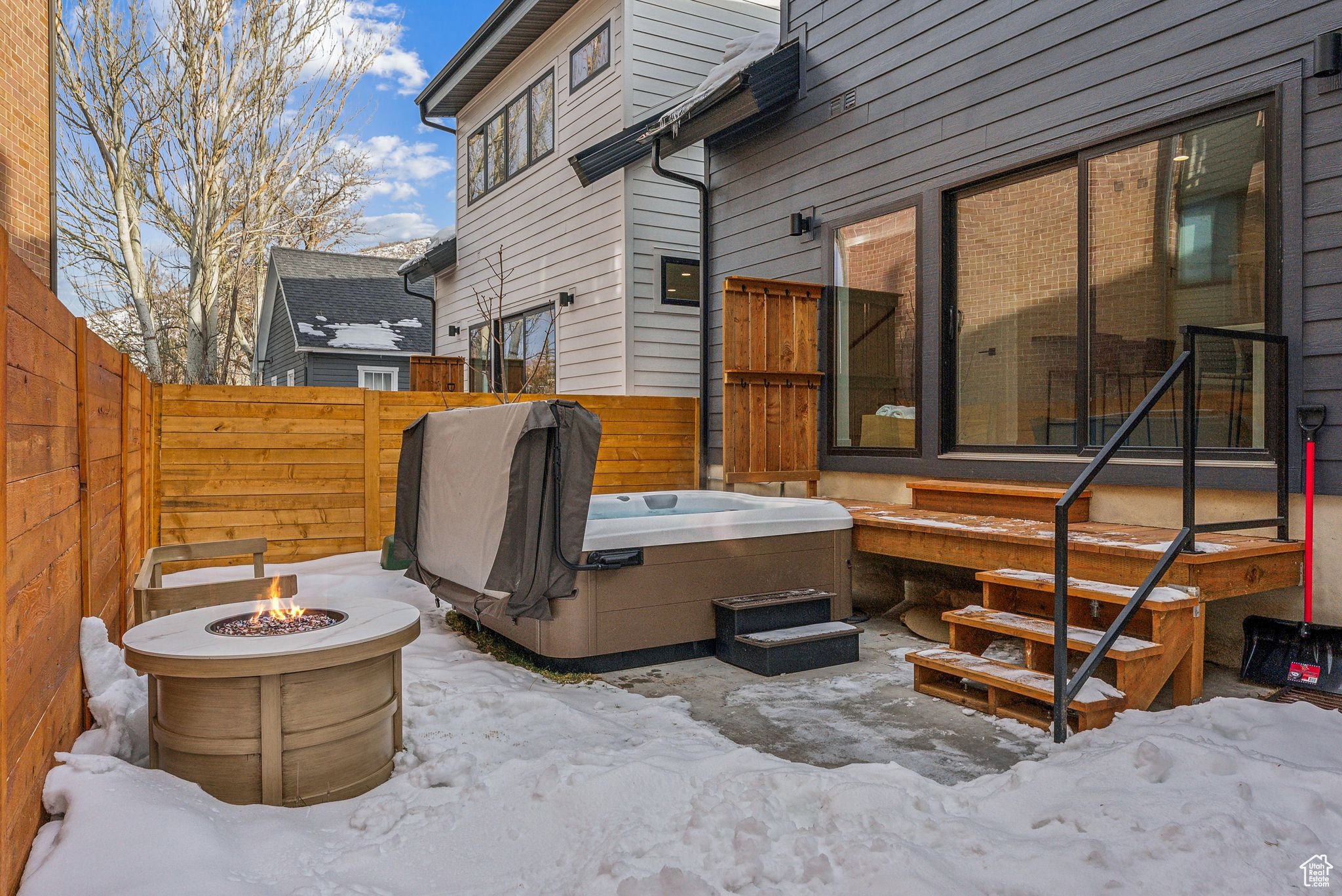 Snow covered patio with a fire pit, area for grilling, and a patio