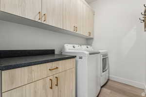 Laundry room featuring cabinet space, washer and dryer, and light wood-style floors
