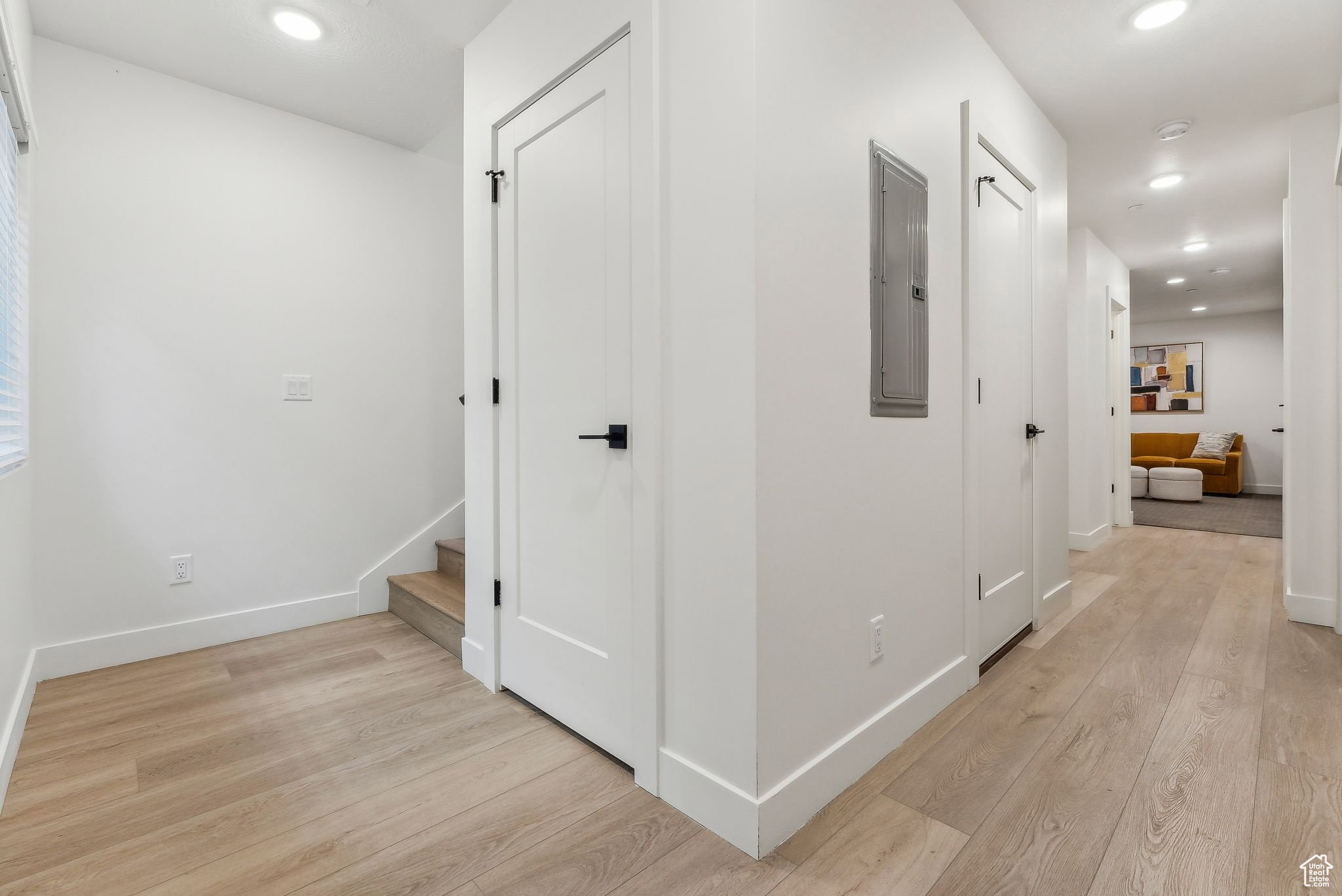 Hall with recessed lighting, light wood-style floors, and electric panel
