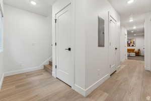 Hall with recessed lighting, light wood-style floors, and electric panel