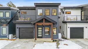 View of front of property featuring concrete driveway, a balcony, and a garage