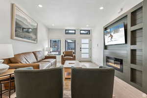 Living room with light wood-type flooring, a fireplace, and recessed lighting