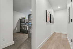 Hallway with light carpet and recessed lighting
