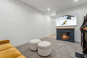 Living area featuring a glass covered fireplace, light carpet, and recessed lighting