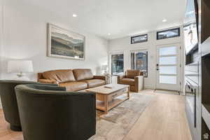 Living room with light wood-style flooring and recessed lighting