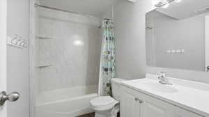 Bathroom with vanity, shower / bath combination with curtain, and a textured ceiling