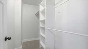 Primary walk in closet with carpet floors