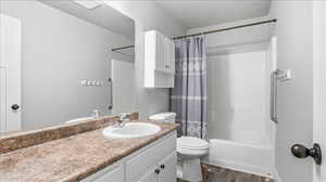 Full bath featuring vanity, shower / tub combo with curtain, and dark wood-type flooring