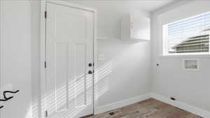 Laundry room with hookup for an electric dryer, light wood-type flooring, and washer hookup.  Entrance to garage.