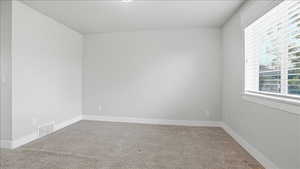 Empty room featuring light colored carpet and baseboards