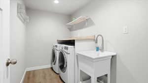 Laundry room featuring light wood-style floors, separate washer and dryer, and recessed lighting