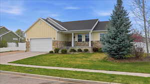 View of front of house featuring stone siding, a porch, board and batten siding, a garage, and concrete driveway