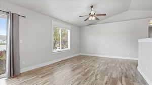 Spare room with light wood-style floors, lofted ceiling, and a ceiling fan