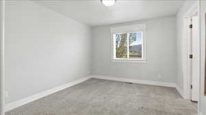Primary bedroom with baseboards and light colored carpet