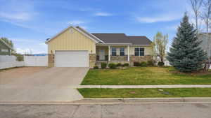 View of front of home with covered porch, board and batten siding, a gate, a garage, and stone siding