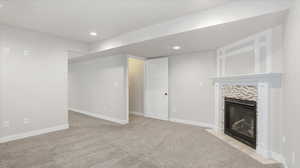 Unfurnished living room featuring light colored carpet, a tile fireplace, and recessed lighting