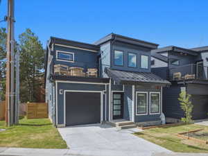 Modern-style residence featuring a dark blue siding exterior, a flat roof, and a second-story balcony with metal railings